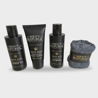 Black bottle of shower gel, shampoo, tube body scrub and light grey face towel